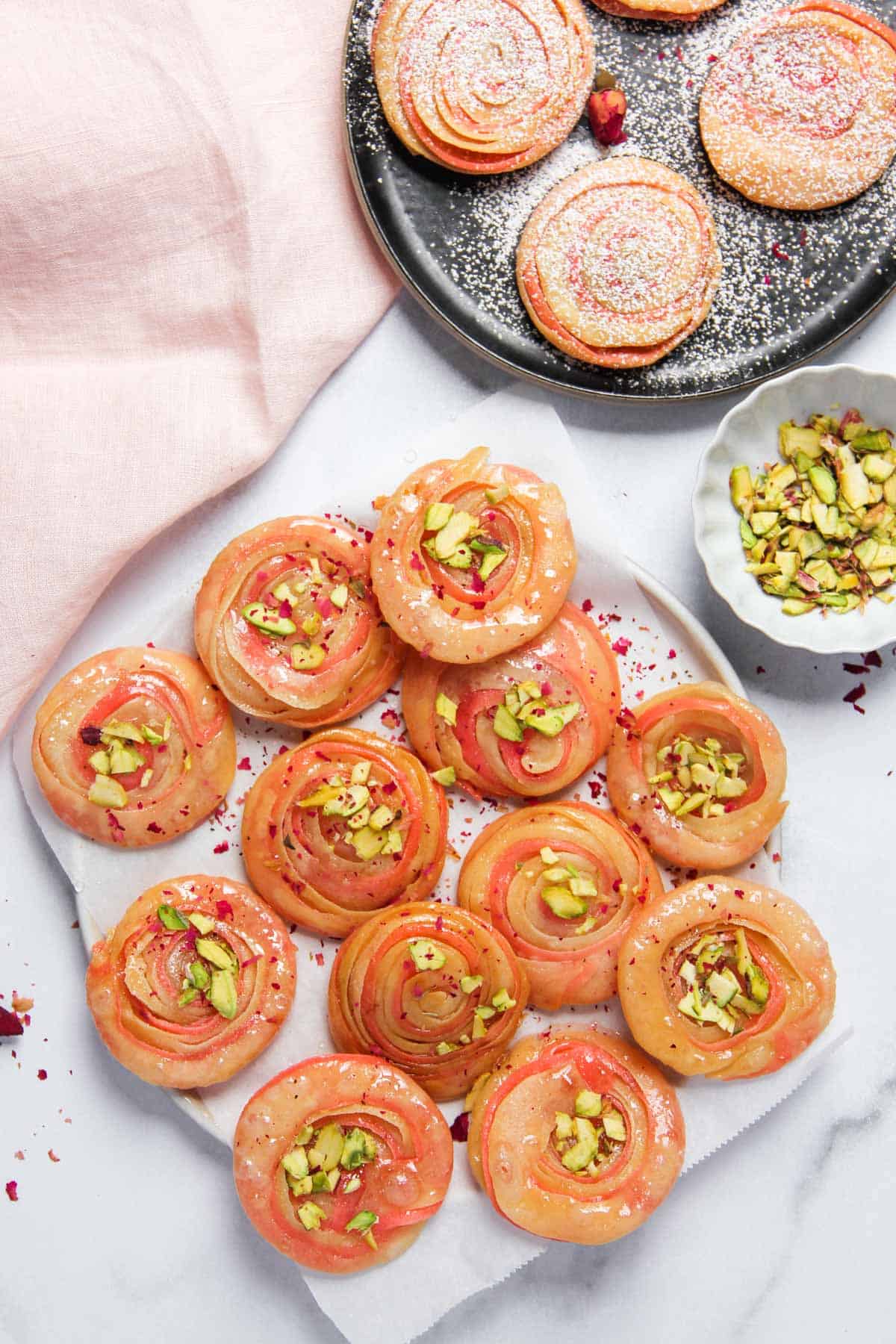 Chirote garnished with pistachios alongside chirote with powdered sugar