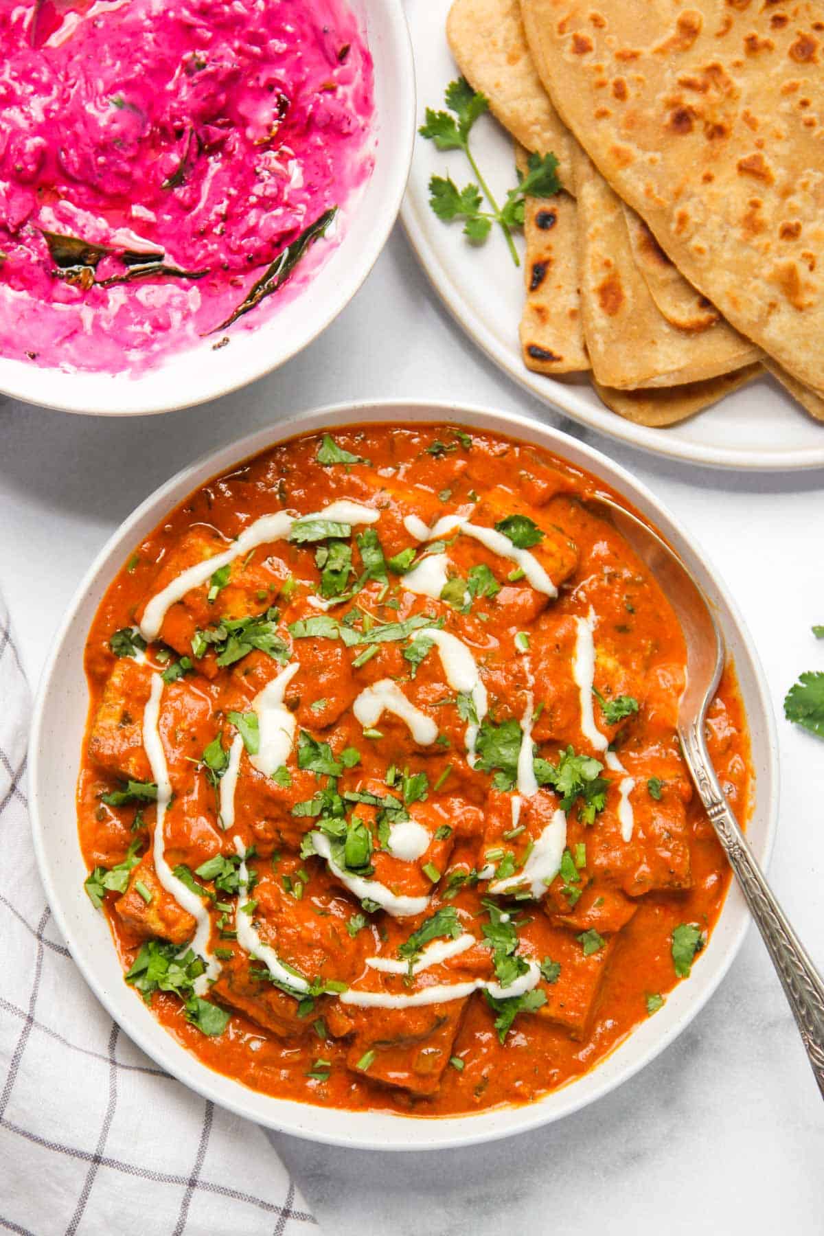 paneer makhani garnished with cilantro and cashew cream 