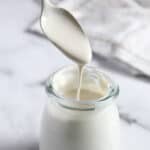 cashew cream dripping from a spoon into a glass bottle