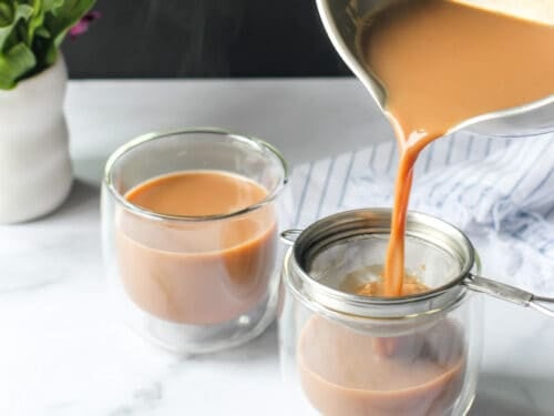 pouring ginger chai in two glass cups