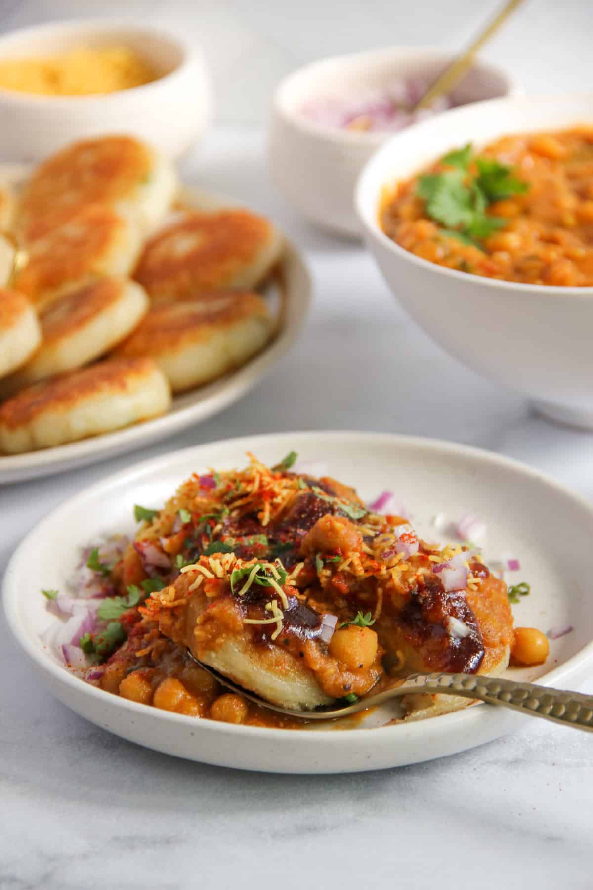 ragda patties served in a white plate garnished with sev and cilantro