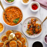 ragda patties served in a white plate with a bowl of curry on the side.