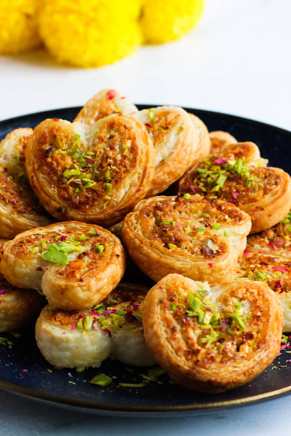 gujiya bites on a serving platter with festive marigold flower background. 