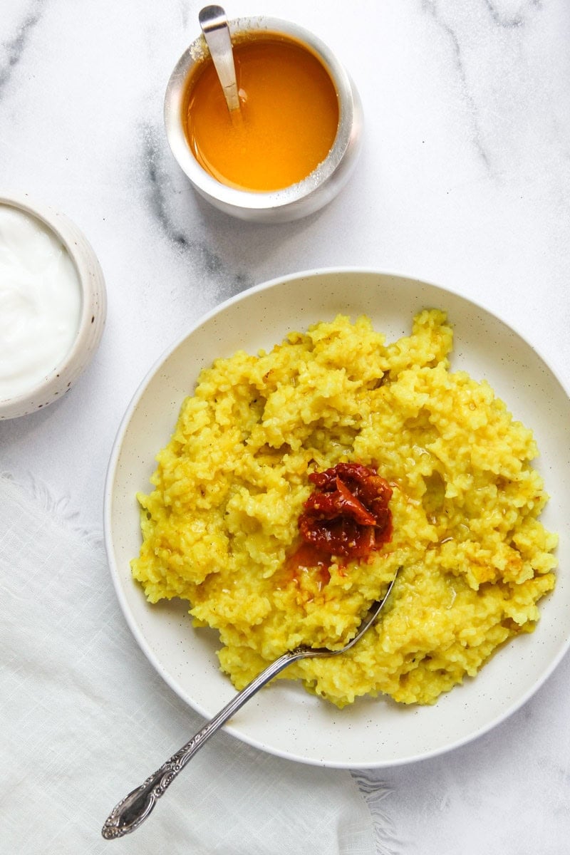 Khichdi served in a white bowl with dahi, achaar and ghee. 