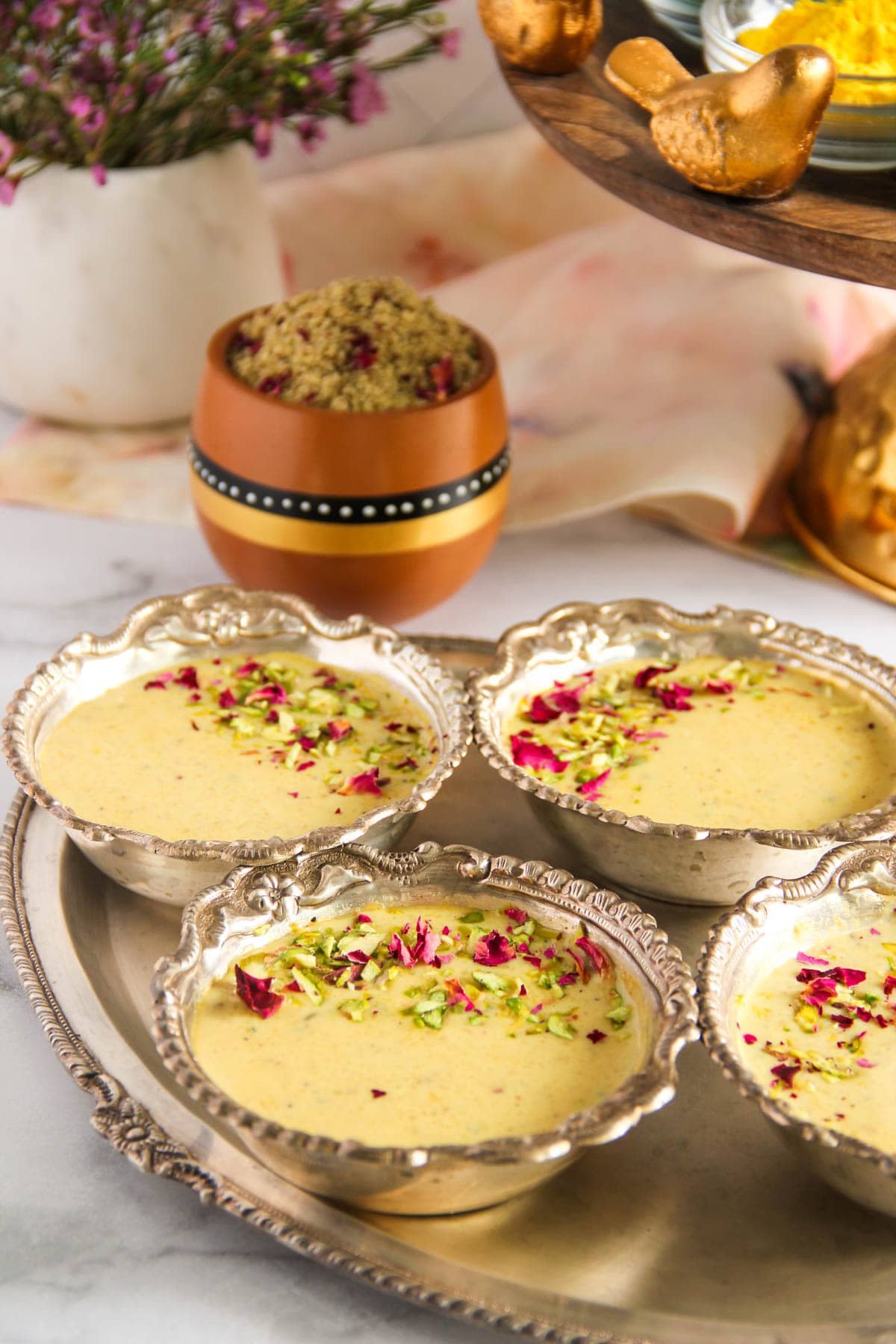 thandai phirni served in bowls garnished with rose petals and pistachios